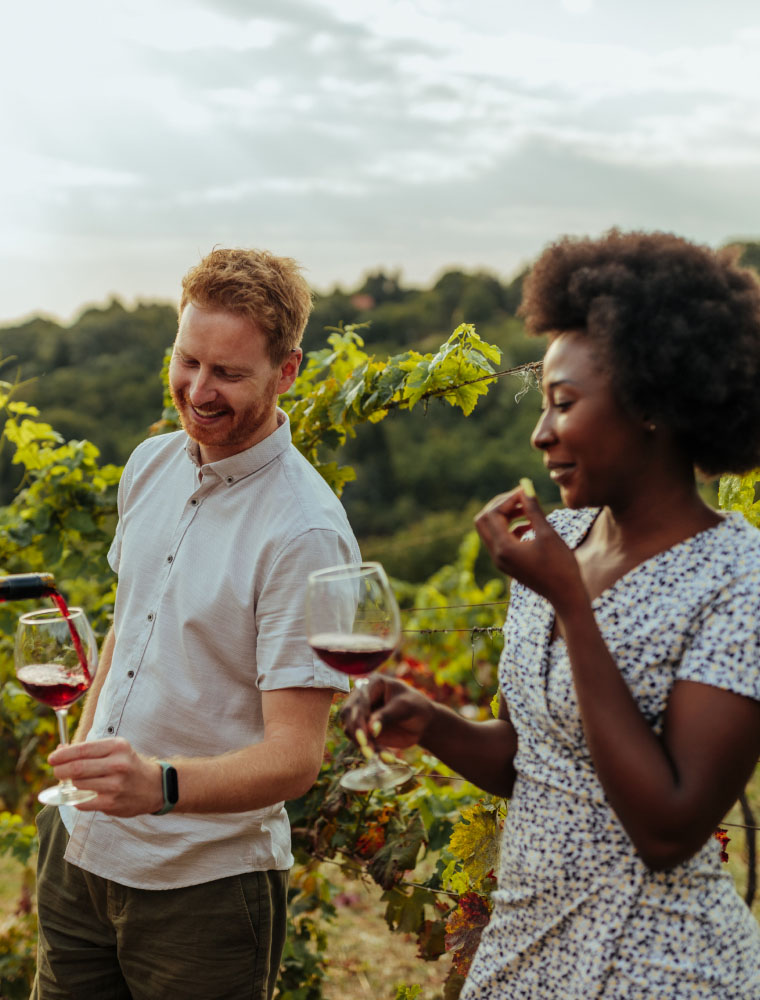 Two people tasting wine in a vineyard